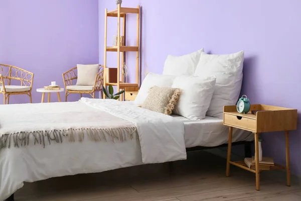 部屋の中のバイオレット壁の近くの快適なベッド ベッドサイドテーブル — ストック写真
