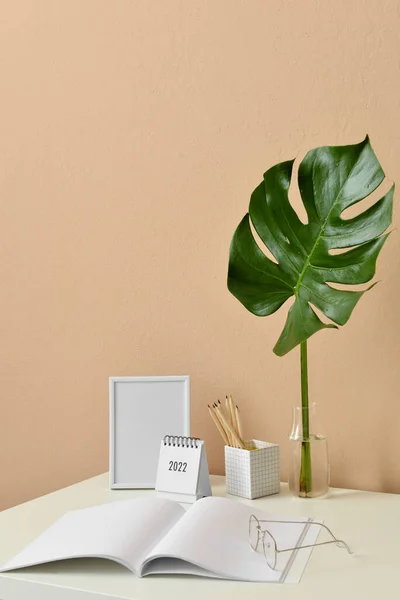 Stylish Workplace Blank Photo Frame Notebook Vase Tropical Leaf Beige — Stock Photo, Image