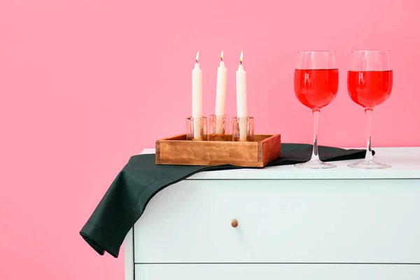 Ποτήρια Κρασιού Και Κεριών Στο Στήθος Κοντά Ροζ Τοίχο — Φωτογραφία Αρχείου