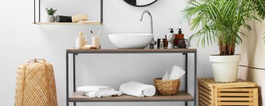 Farklı banyo aksesuarları ve ışık duvarının yanında modern lavabosu olan bir masa.