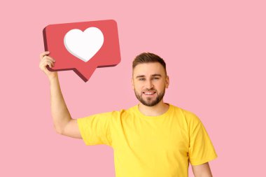 Pembe arka planda kalbi olan yakışıklı bir genç adam konuşma baloncuğu tutuyor. Hoşlanma Konsepti