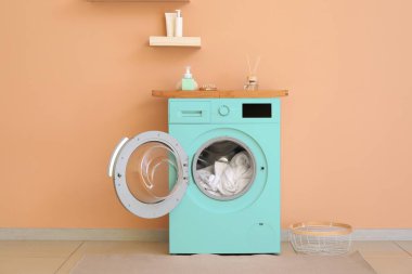 Renk duvarının yanında modern turkuaz çamaşır makinesi
