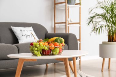 Oturma odasındaki kanepenin yanındaki meyve sepetli masa.