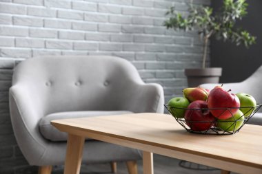 Oturma odasındaki koltuğun yanındaki masada meyve sepeti.