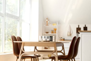 Boş bardaklarla dolu tepsi yemek masasında, aydınlık odada.