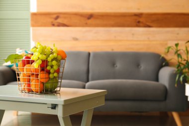 Şık oturma odasındaki kanepenin yanındaki masada meyve sepeti.