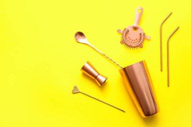Sarı arka planda farklı bakır kokteyl aletleri.