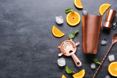 Kokteyl malzemeleri, ayakkabı sallayıcısı, çifte jigger, süzgeç ve koyu arkaplanda karıştırma kaşığı.