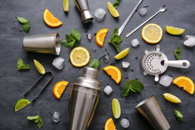 Koyu arkaplanda barmen aletleri ve kokteyl malzemeleri var.