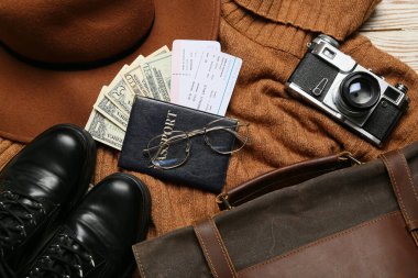 Paralı pasaport, biletler, fotoğraf makinesi ve hafif ahşap arka planda rehberin eşyaları.