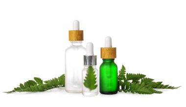 Beyaz arka planda izole edilmiş doğal serum ve eğrelti otu yaprakları şişeleri.