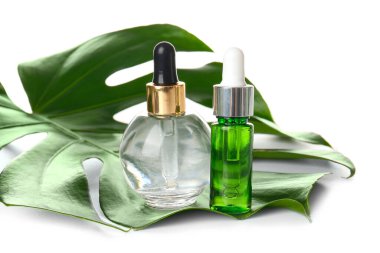 Beyaz arka planda doğal serum ve palmiye yaprağı şişeleri, yakın plan.