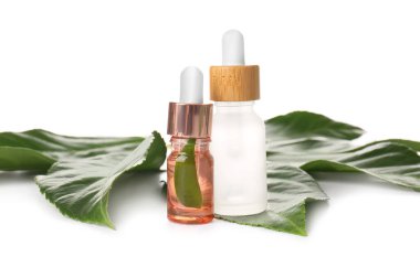 Beyaz arka planda doğal serum ve bitki yaprağı şişeleri