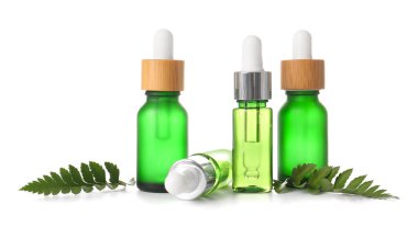Beyaz arka planda yalıtılmış eğreltiotu yapraklı doğal serum şişeleri.