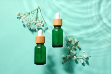 Renkli arka planda su içinde doğal serumlar ve çigila çiçekleri.