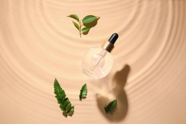 Bir şişe doğal serum ve bitki yaprakları renk arka planında suda.