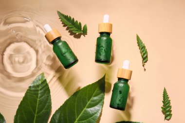 Doğal serum ve bitki yaprakları renkli arkaplanda suya konur.