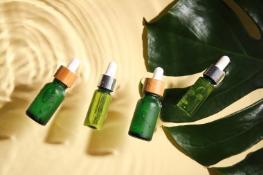 Renkli suda doğal serum ve palmiye yaprağı şişeleri.