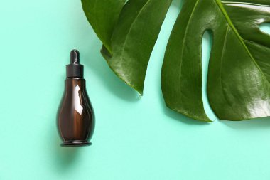 Bir şişe doğal serum ve arka planda palmiye yaprağı.