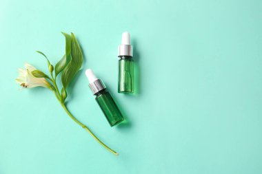 Renkli arkaplanda doğal serum ve çiçek şişeleri