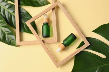 Renk arkaplan üzerinde doğal serum şişeleri ve boş resim çerçeveleri ile kompozisyon