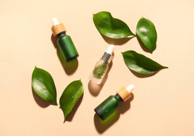 Renkli arkaplanda doğal serum ve bitki yaprakları şişeleri