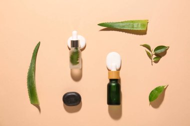 Doğal serum şişeleri, spa taşları ve bitki yapraklarıyla renklendirilmiş.