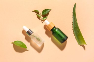 Renkli arkaplanda doğal serum ve bitki yaprakları şişeleri