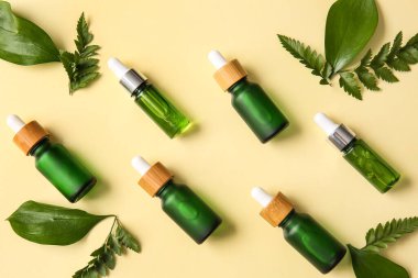 Renkli arka planda farklı doğal serum ve bitki yaprakları şişeleri