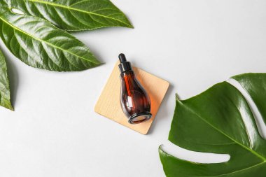 Beyaz zemin üzerinde doğal serum ve bitki yaprakları olan bileşim