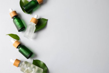 Beyaz arka planda farklı serum ve bitki yaprakları içeren kompozisyon
