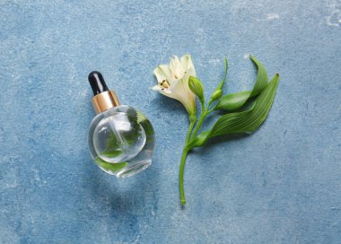 Renkli arka planda bir şişe doğal serum ve alstroemeria çiçeği.