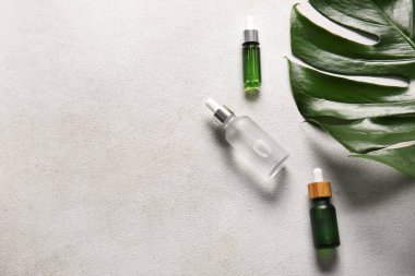 Hafif arka planda doğal serum ve palmiye yaprağı şişeleri.