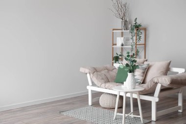 İçinde kanepe ve vazoda okaliptüs olan aydınlık bir oturma odası.