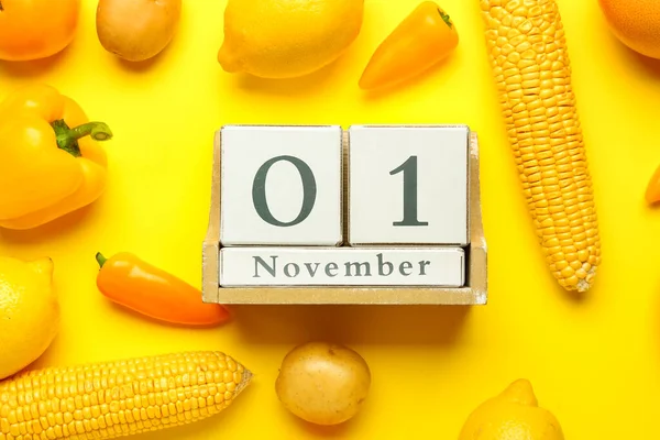 日付木製のキューブカレンダー11月1日 黄色の背景に新鮮な野菜や果物 世界ビーガン日のコンセプト — ストック写真