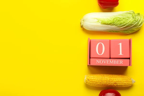 黄色の背景に日付11月1日と中国のキャベツ ピーマン トウモロコシ キューブカレンダー 世界ビーガン日のコンセプト — ストック写真