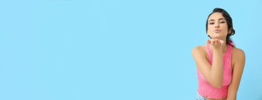 Yüzünde sim olan çekici genç bir kadın açık mavi arkaplanı öpüyor ve mesaj için yeri var.