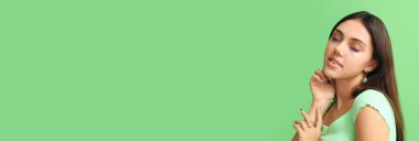 Yeşil arka planda parlak makyajlı güzel bir genç kadın.