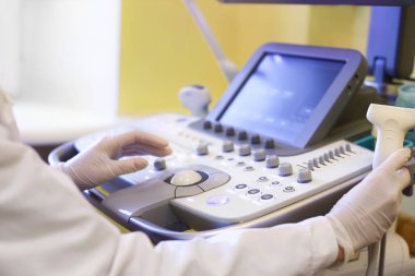Klinikte ultrason cihazı kullanan bir doktor.