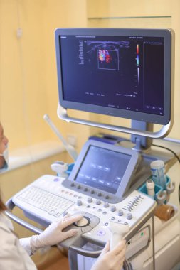 Klinikte ultrason cihazı kullanan bir doktor.
