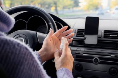 Arabada dezenfektan kullanan kadın sürücü