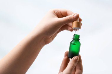 Arka planda serum şişesi olan kadın eller, yakın plan.