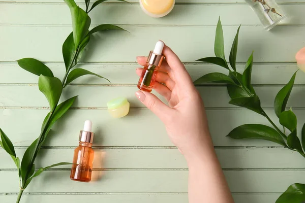 Vrouwelijke Hand Met Flessen Natuurlijk Serum Cosmetica Planten Takken Kleur — Stockfoto