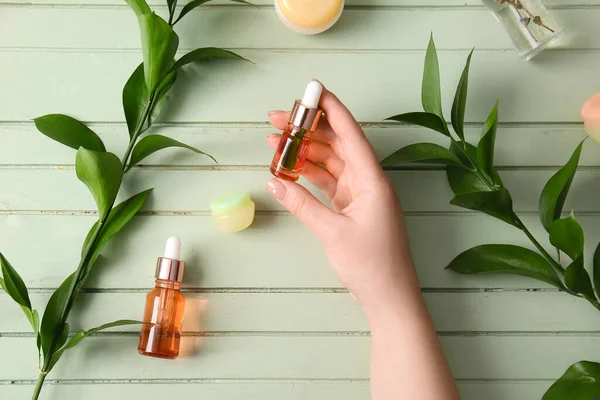 Mão Feminina Com Garrafas Soro Natural Cosméticos Ramos Plantas Fundo — Fotografia de Stock