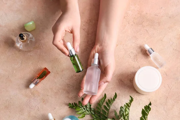 Kvinnliga Händer Med Flaskor Naturligt Serum Och Kosmetika Färg Bakgrund — Stockfoto