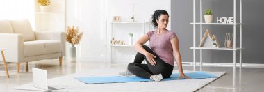 Dizüstü bilgisayarı olan sportif bir kadın evde yoga yapıyor. Çevrimiçi eğitim kavramı