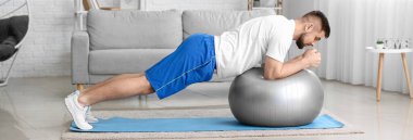 Sportif genç adam evde fitbol antrenmanı yapıyor.