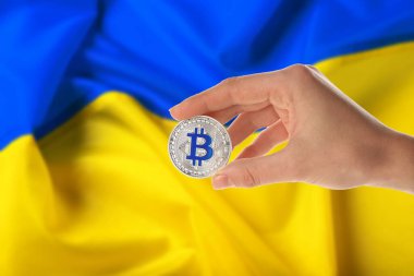  Ukrayna bayrağına karşı Bitcoin tutan kadın.
