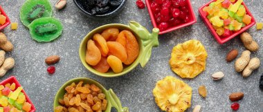 Gri arka planda farklı kurutulmuş meyve ve fındıklı kaseler.