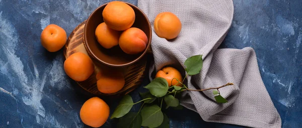 Mavi arka planda bir kase lezzetli olgun kayısı. 